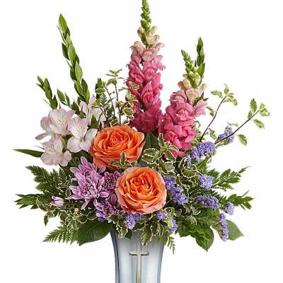 Mixed bouquet of roses, snapdragons, and purple flowers in a silver vase