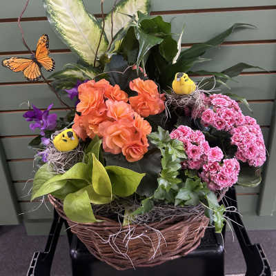 Basket arrangement with orange and pink flowers, butterflies, and small bird nests