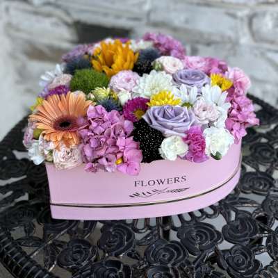 Mixed pastel flower arrangement in a pink heart-shaped box