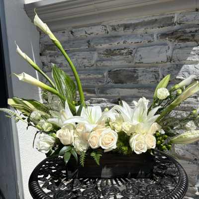 White roses and lilies in a black rectangular container