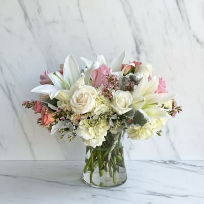 Pink and white bouquet with lilies and roses in a clear glass vase