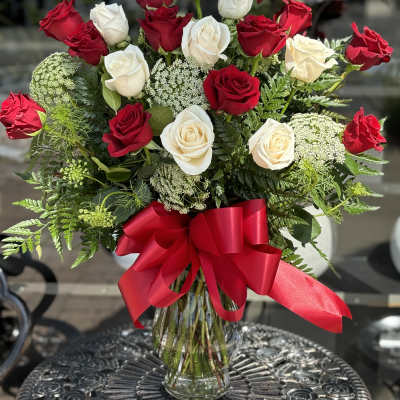 Red and white roses in a glass vase with a red ribbon