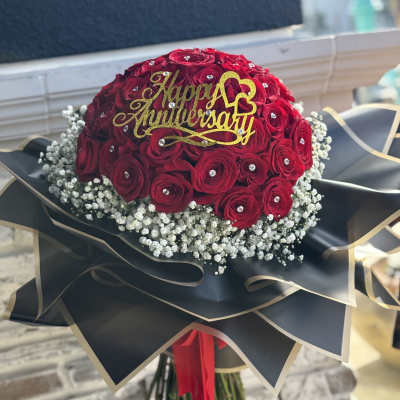 Red rose bouquet with a gold Happy Anniversary topper