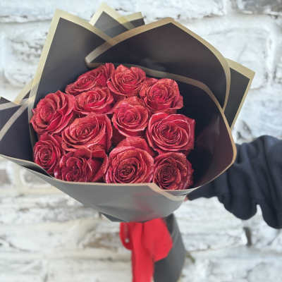Bouquet of red roses wrapped in black paper with a red ribbon