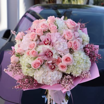 Large pink and white bouquet with roses and orchids wrapped in pink paper