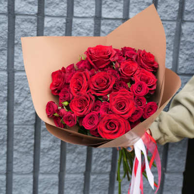Bouquet of red roses wrapped in tan paper with red and white ribbons
