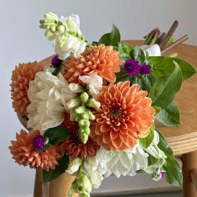 Bouquet of orange and white flowers with green leaves on a wooden chair