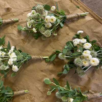 Small white flower bouquets with green foliage wrapped in twine