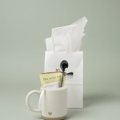 White mug gift set with tea packet and spoon in a paper bag