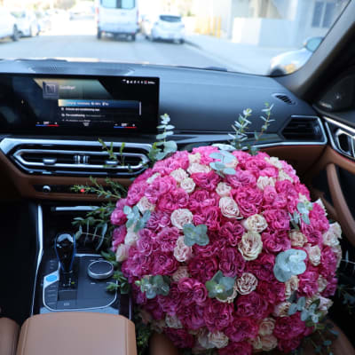 Large pink and cream rose bouquet resting on a car seat