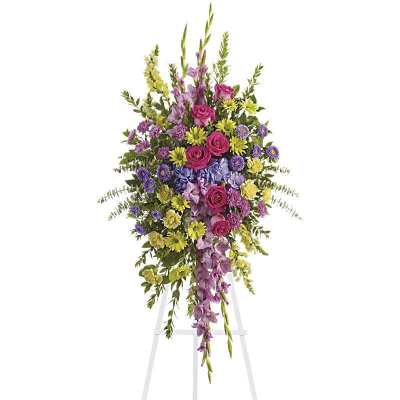 Tall standing floral spray with pink, purple, and yellow flowers on a white easel