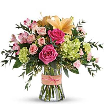 Pink roses and lilies arranged in a glass vase with green filler
