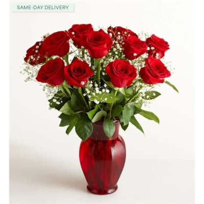 Red roses arranged in a red glass vase with baby's breath