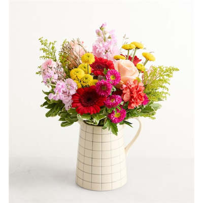Mixed bouquet of colorful flowers in a cream checkered pitcher
