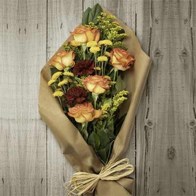 Bouquet of orange roses and red carnations wrapped in brown paper