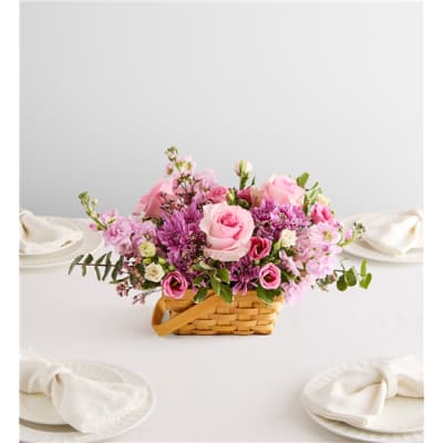 Pink and purple flower arrangement in a woven basket on a table