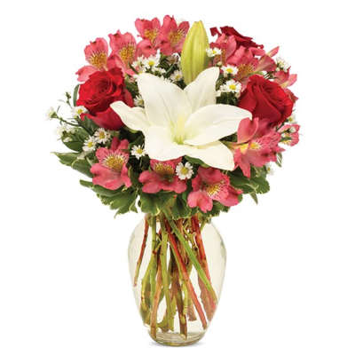 Bouquet of red roses, pink alstroemeria, and white lilies in a glass vase