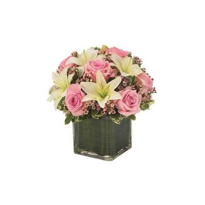 Pink roses and white lilies arranged in a square glass vase