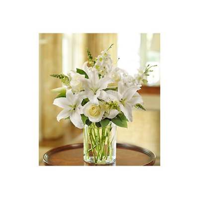 White lilies and roses arranged in a clear glass vase