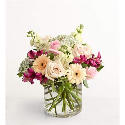 Mixed pink and cream flowers arranged in a clear glass vase