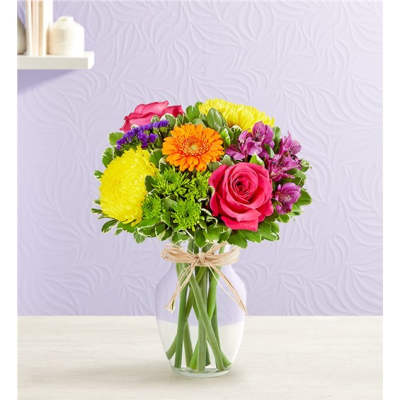 Colorful mixed bouquet in a clear glass vase with a twine bow