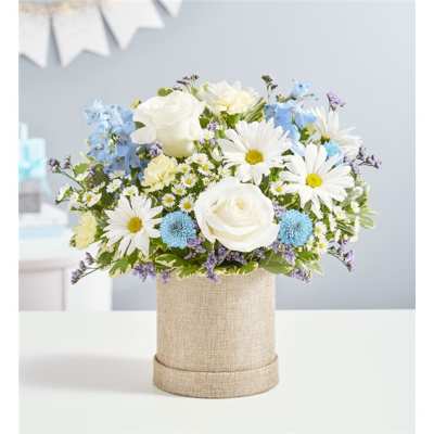 White roses and daisies in a burlap-covered cylinder vase
