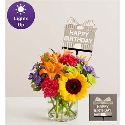 Bright mixed bouquet in a glass vase with a Happy Birthday sign