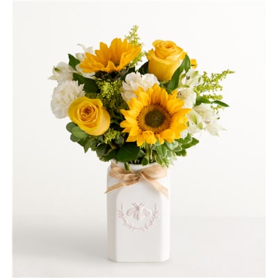 Yellow roses and sunflowers in a white vase with a ribbon