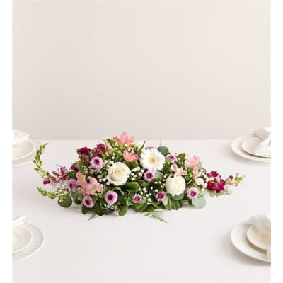 Low floral centerpiece with pink and white blooms on a table