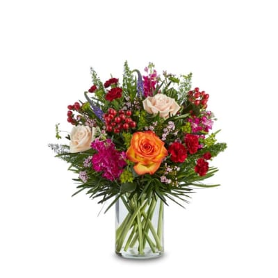 Mixed bouquet of roses, carnations, and purple flowers in a glass vase
