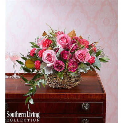 Pink roses and carnations arranged in a woven basket on a table