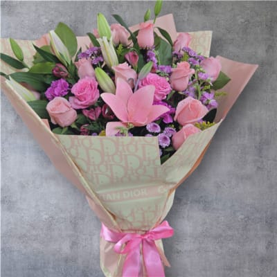 Pink rose and lily bouquet wrapped in patterned paper with a pink ribbon