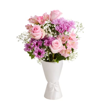 Pink roses and purple daisies in a white vase with a bow