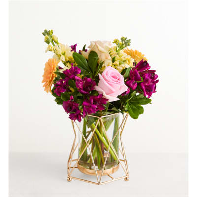 Mixed bouquet of pink, purple, and yellow flowers in a glass vase