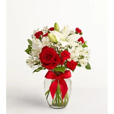 Red roses and white lilies in a glass vase with a red ribbon