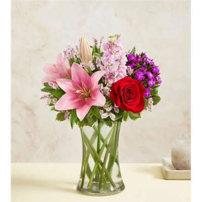 Pink lilies and a red rose in a clear glass vase