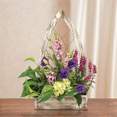 Purple and pink flowers arranged in a rustic wooden basket with a handle