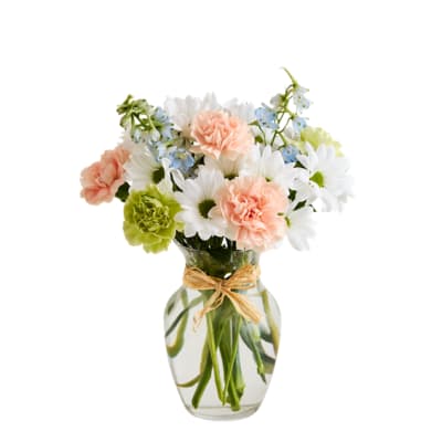 Bouquet of white daisies, peach carnations, and blue flowers in a glass vase