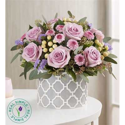 Lavender roses and small pink flowers in a patterned white vase