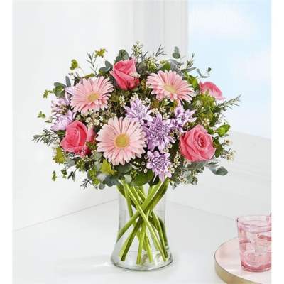 Pink roses and daisies arranged in a clear glass vase