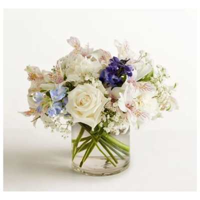 White roses and mixed pastel flowers arranged in a clear glass vase