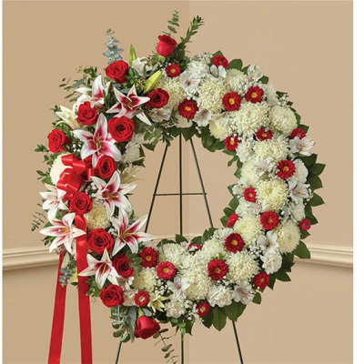 Large floral wreath with red roses and white flowers on a stand