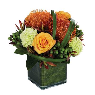 Orange roses and green pom-pom flowers in a square glass vase