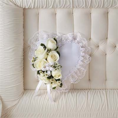 White rose bouquet with lace trim and ribbon on a cream tufted chair