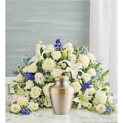 White floral funeral arrangement with a silver urn in front
