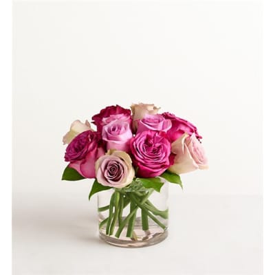 Pink and magenta roses arranged in a clear glass vase