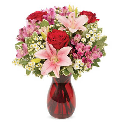 Bouquet of red roses and pink lilies in a red glass vase