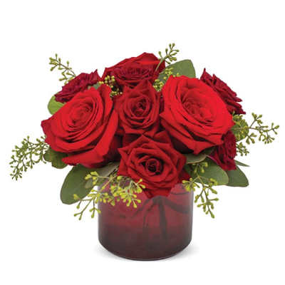 Red roses arranged in a glass vase with green accents