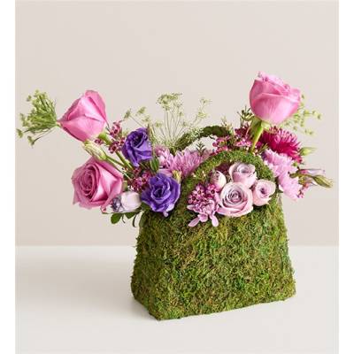 Pink and purple roses arranged in a moss-covered container