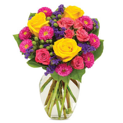 Bouquet of yellow and pink roses with magenta daisies in a glass vase